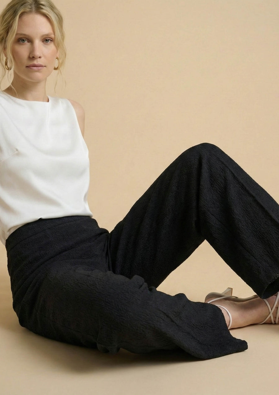 Lifestyle-Aufnahme der schwarzen Hose 'Pradera' im Sitzen. Die entspannte Passform (Relaxed Fit) sorgt für souveränen Komfort vom Homeoffice bis zum Abend.