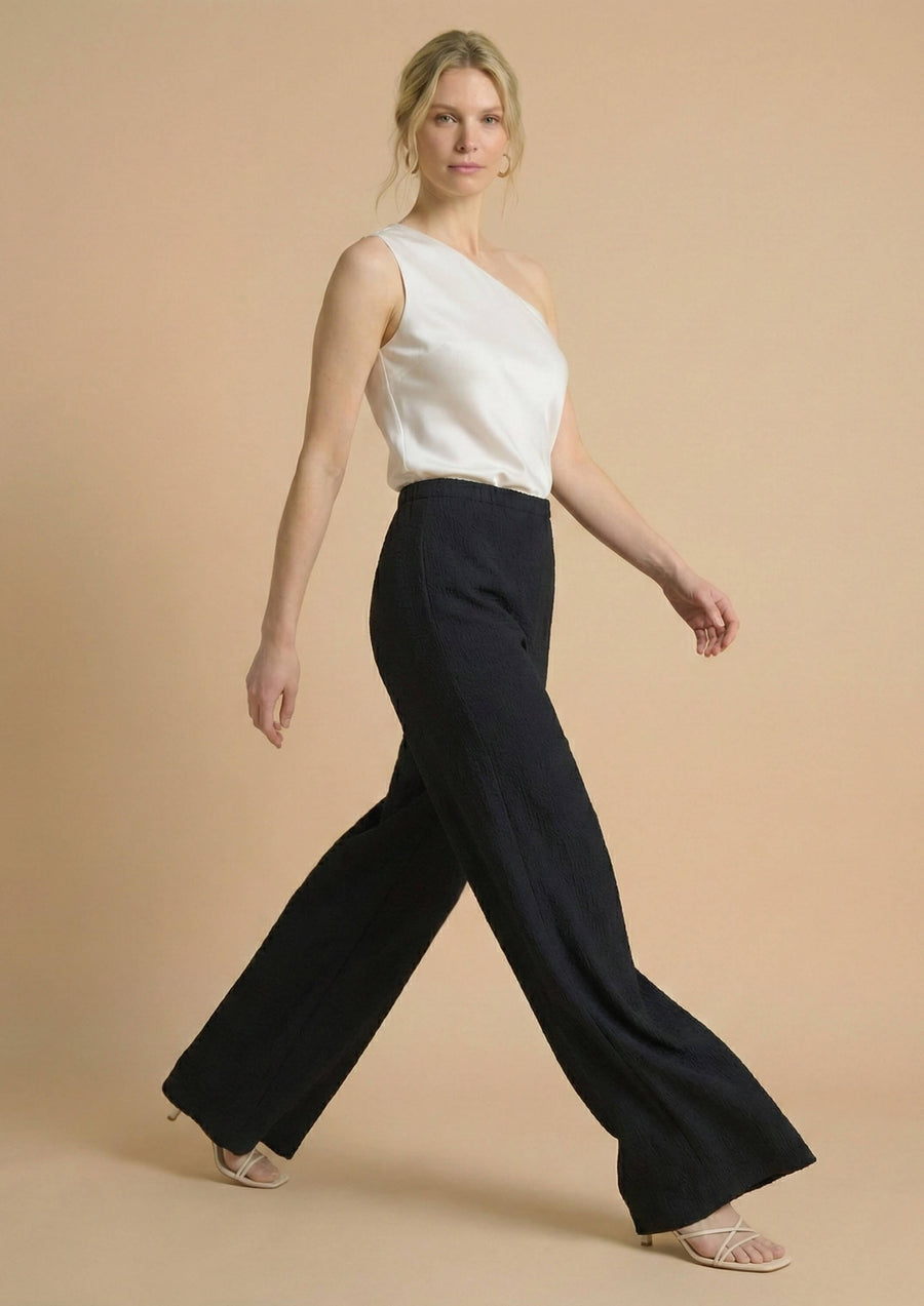 Das Model präsentiert die schwarze Ayni Ppacha Hose 'Pradera' im dynamischen Gang. Der High-Waist-Schnitt und das gerade Bein (Straight Leg) definieren eine kraftvolle, moderne Silhouette.