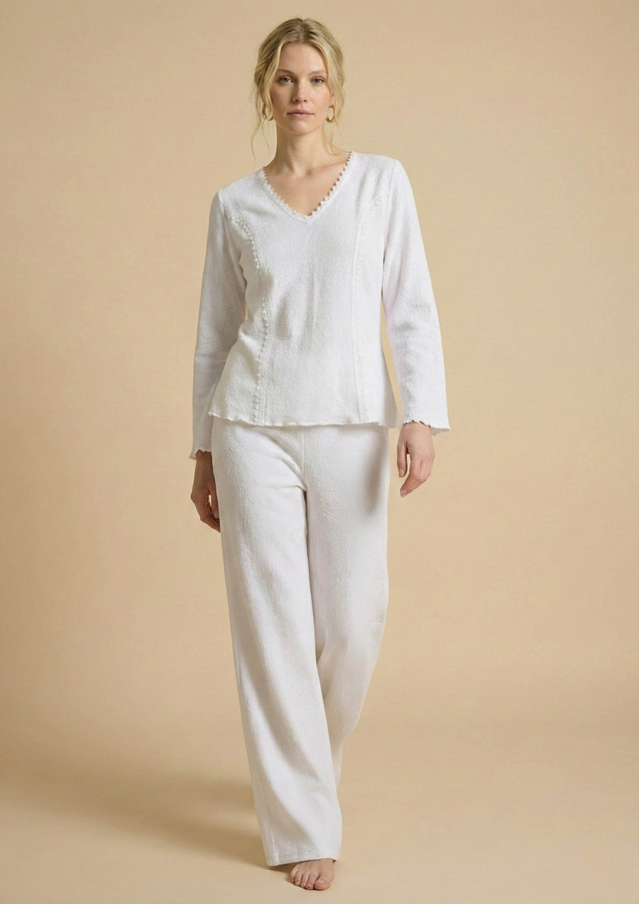 Frontale Ansicht der weißen Hose 'Pradera' von Ayni Ppacha getragen von einem Model. Der strukturierte Baumwollwebstoff mit eingewebten Nazca-Symbolen betont den hochwertigen Straight-Leg-Schnitt.