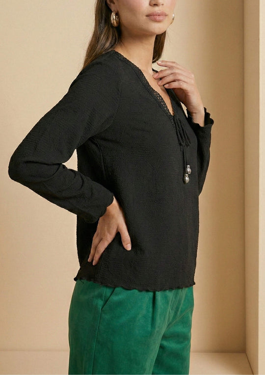 Seitenansicht der Bluse 'Duria' von Ayni Ppacha. Der strukturierte Baumwollwebstoff mit eingewebten Nazca-Symbolen verleiht der schwarzen Oberfläche eine haptische Tiefe.