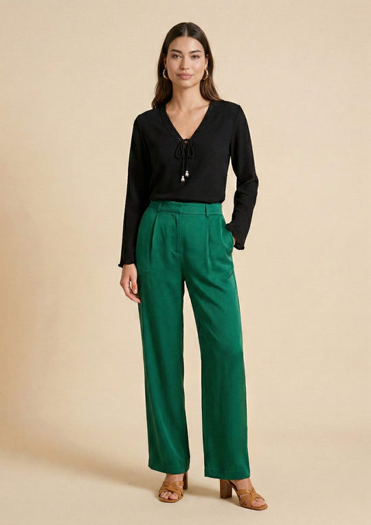 Ganzkörperansicht der schwarzen Bluse 'Duria' im Loose Fit, kombiniert mit einer smaragdgrünen Hose. Ein souveräner Look, der die Vielseitigkeit des Nazca-Webstoffs zeigt.