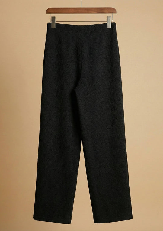 Die schwarze Hose 'Pradera' von Ayni Ppacha aus strukturiertem Nazca-Baumwollwebstoff am Bügel. Sichtbar sind der präzise Straight-Leg-Schnitt und die grafische Tiefe der eingewebten Symbolik.