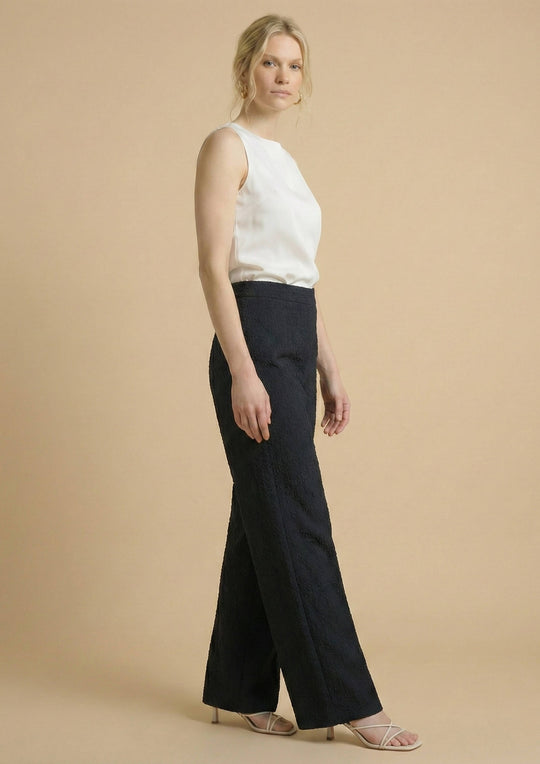 Seitliche Ansicht der schwarzen Hose 'Pradera' am Model. Die Aufnahme zeigt die haptische Signatur des Nazca-Webstoffs und die feine Struktur der peruanischen Baumwolle.