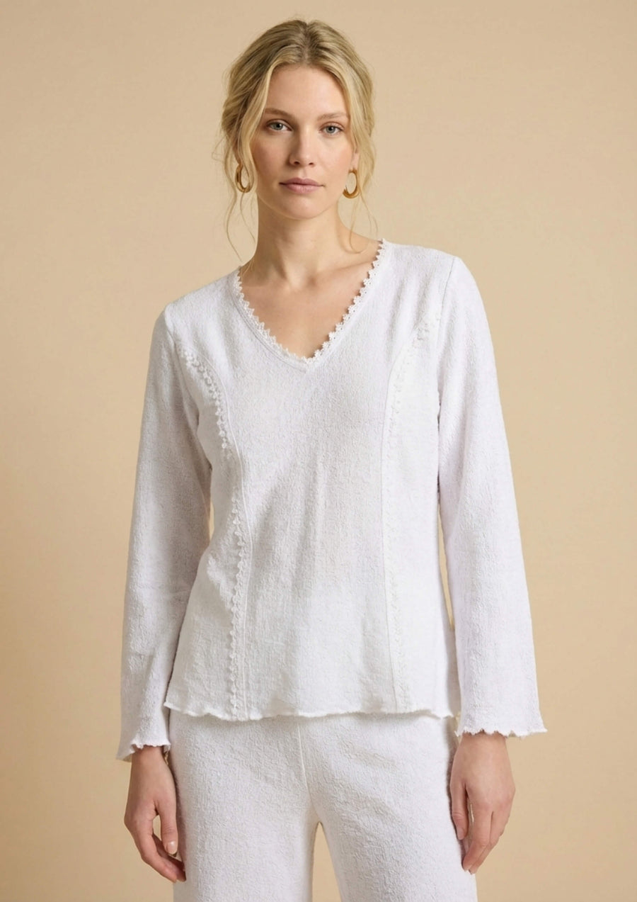Weiße Baumwollbluse 'Airosa' von Ayni Ppacha mit eingewebten Nazca-Symbolen. Der V-Ausschnitt und die Ziernähte sind mit einer filigranen Häkelkante (Crochet) veredelt, die den eleganten Charakter betont.
