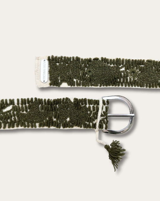 Beide Enden des Gürtels Gírgola: silberfarbene D-Schnalle mit Quaste und Metallplakette mit Schriftzug Ayni Ppacha