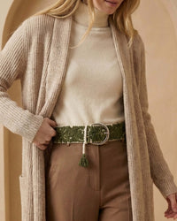 Nahaufnahme der abgerundeten silbernen Metallschnalle und der dunkelgrünen Quaste am Gürtel 'Gírgola', die die hochwertige Handarbeit aus Peru unterstreicht.