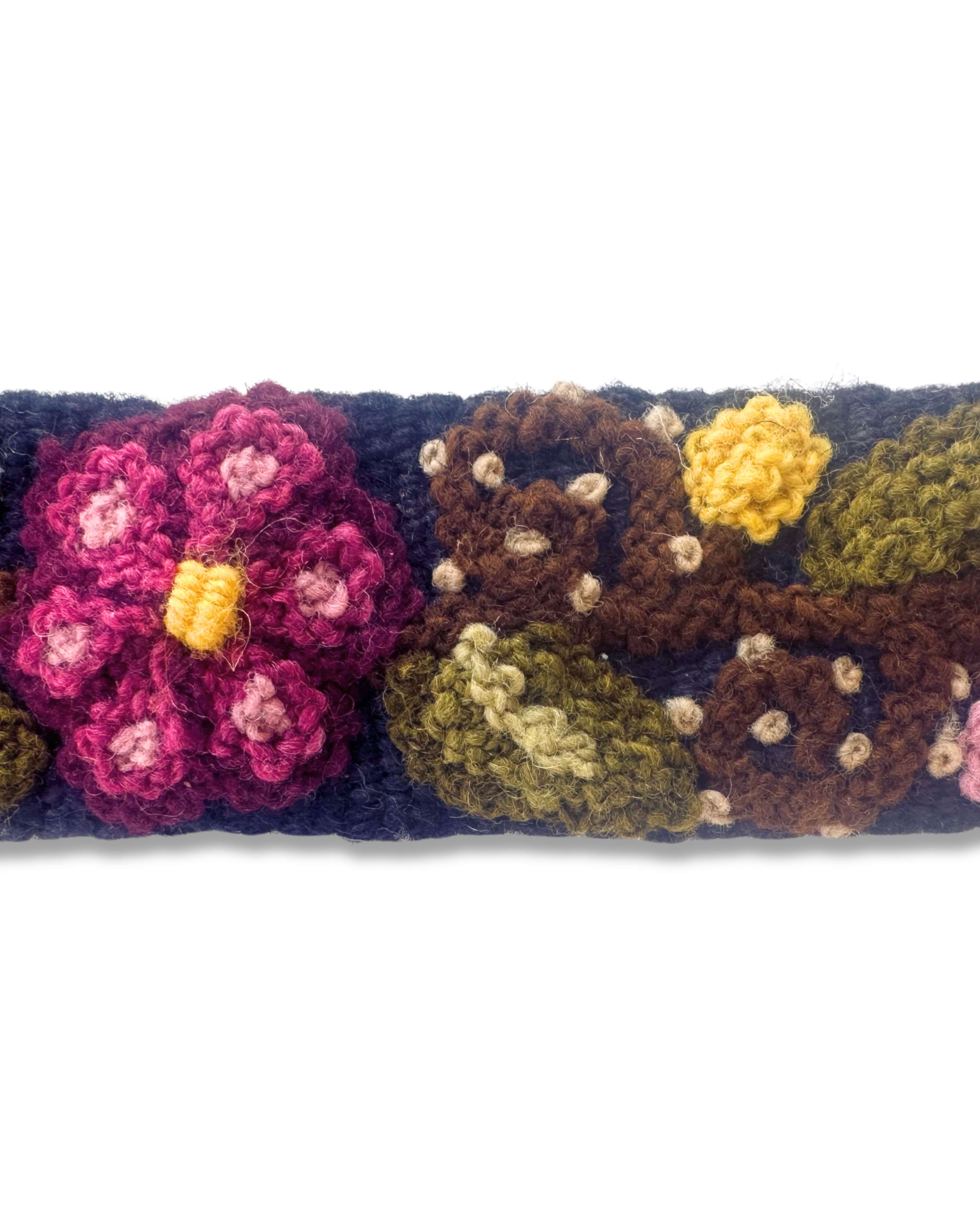 Nahaufnahme der feinen Handstickerei des dunkelblauen Gürtels 'Ilusión', die die Textur der natürlich gefärbten Wolle und die detailreichen bunten Stickmotive in gedeckten Farben zeigt.