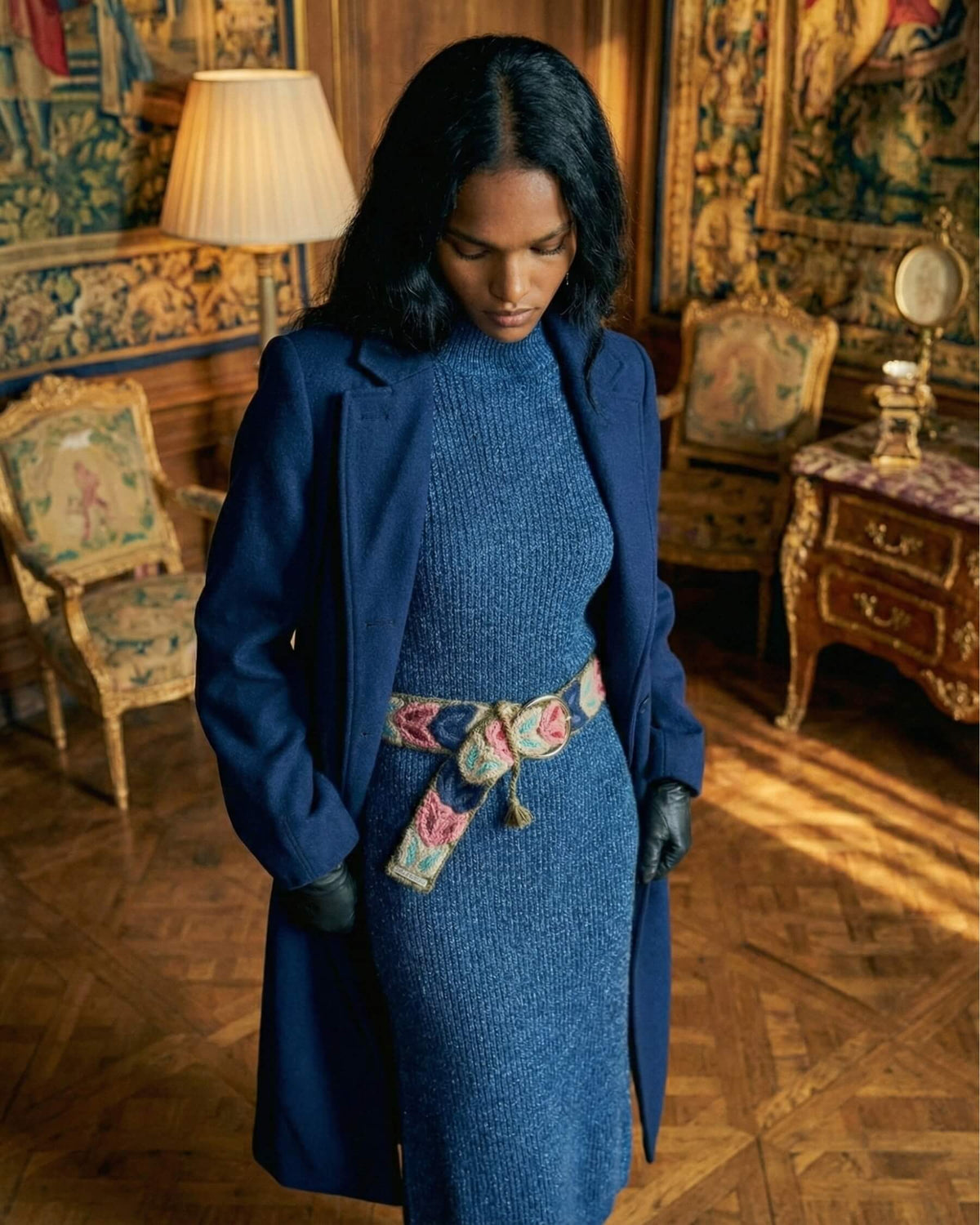 Atmosphärische Aufnahme des handgefertigten Gürtels 'Morera', der einem klassischen blauen Winter-Outfit eine verspielte, florale Note verleiht.