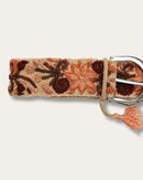 Gürtel Otoño von Ayni Ppacha, Nahaufnahme an der Schnalle: sandfarbene Schafwolle, handbestickt mit Blüten und Ranken in Terrakotta, Apricot und Rotbraun, silberfarbene D-Schnalle mit Quaste
