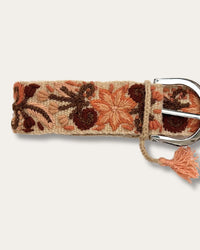 Gürtel Otoño von Ayni Ppacha, Nahaufnahme an der Schnalle: sandfarbene Schafwolle, handbestickt mit Blüten und Ranken in Terrakotta, Apricot und Rotbraun, silberfarbene D-Schnalle mit Quaste