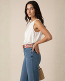 Profilansicht des floral bestickten Gürtels 'Ponsetia'. Die Aufnahme zeigt, wie das Accessoire aus peruanischer Schafwolle die Taille definiert und einem urbanen Denim-Look eine kunstvolle Tiefe verleiht.