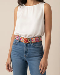 Der handbestickte Gürtel 'Ponsetia' von Ayni Ppacha aus orangener Schafwolle. Das detailreiche florale Muster in Rot, grün und Pink bildet einen lebendigen Kontrast zu Blue Jeans und einem schlichten weißen Top.