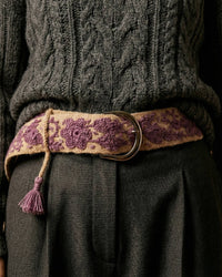 Harmonischer Materialmix: Der handgefertigte Gürtel 'Violeta' aus Wolle setzt einen farbigen Akzent in Violett auf einem grauen Winter-Outfit.