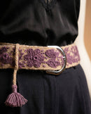 Nahaufnahme der lila Handstickerei aus natürlich gefärbter Wolle auf dem Gürtel 'Violeta', die die hochwertige Textur und die silberne Schnalle zeigt.