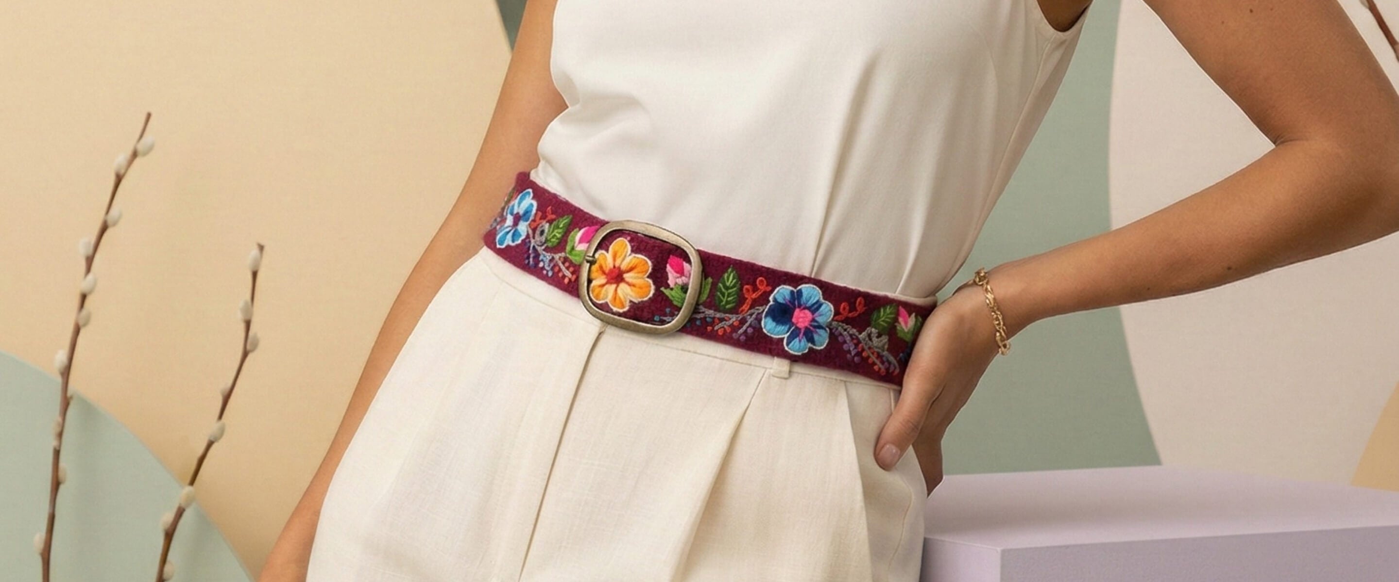 Ayni Ppacha Homepage Hero Image für die Frühjahrs-Kollektion 2026. Elegantes Damen-Outfit mit einem handgefertigten, floral bestickten Gürtel aus peruanischer Hochlandwolle. Souveräner Ausdruck und textile Meisterschaft, bekannt aus Herzstück, Journal Frankfurt und Silver Caramel.