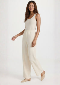 Model in Bewegung trägt die beige Hose 'Pradera' aus der Ayni Ppacha Kollektion. Der Relaxed Fit bietet souveränen Komfort und macht die Hose zum idealen Essential für Business und Reise.