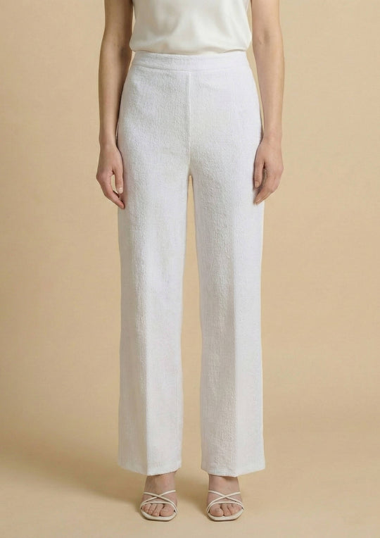 Frontalansicht der weißen Hose 'Pradera' von Ayni Ppacha aus strukturiertem Nazca-Baumwollwebstoff. Der High-Waist-Schnitt und das gerade Bein (Straight Leg) betonen die elegante, minimalistische Silhouette.