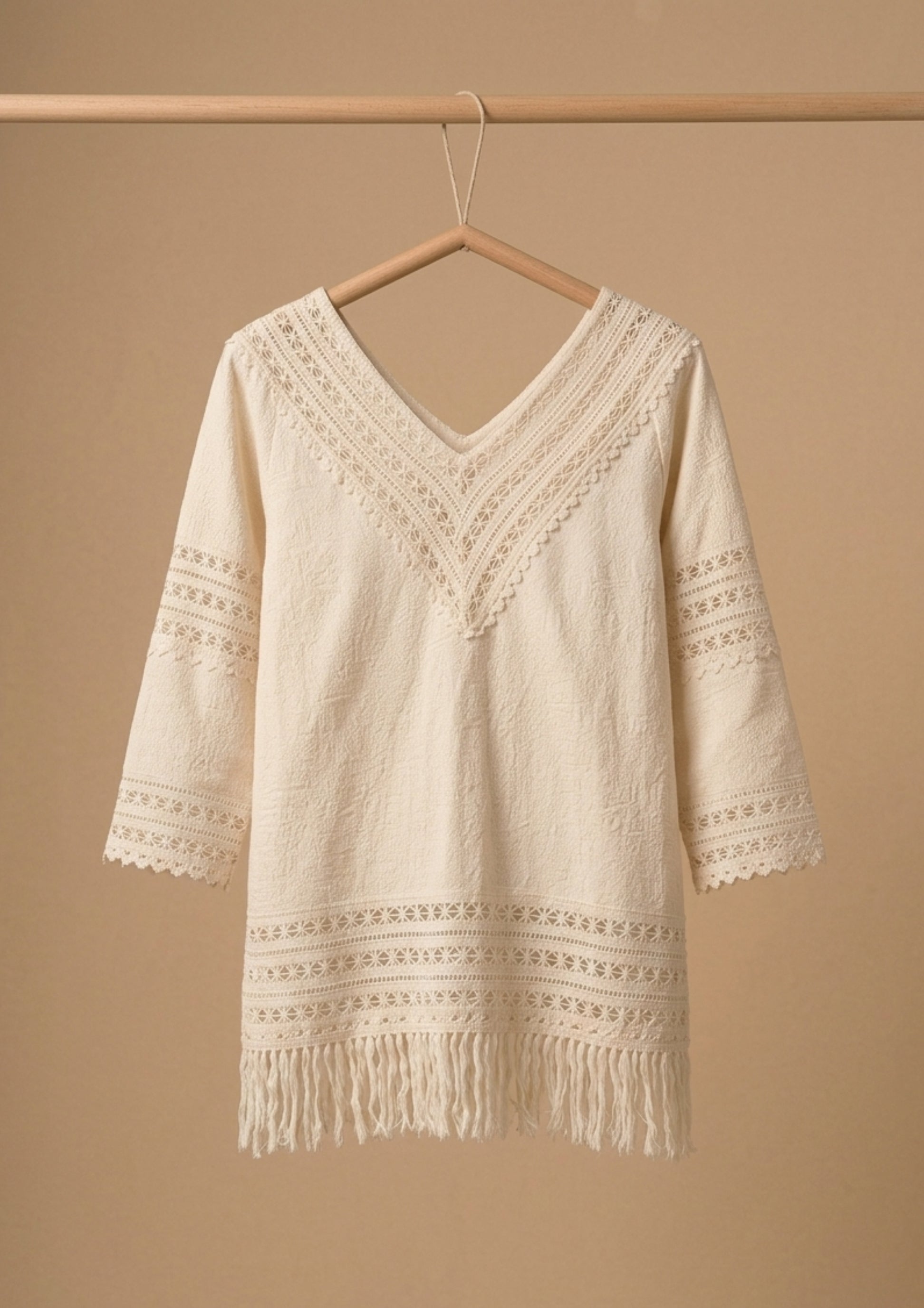 Die Jacquard-Bluse 'Rubí' von Ayni Ppacha aus 100 % ungefärbter Tanguis-Baumwolle am Bügel. Sichtbar sind die filigranen Häkeleinsätze und die handwerklich inspirierten Fransen.