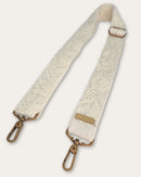 Coco bag strap by Ayni Ppacha laid out diagonally: natural white sheep wool with tone-on-tone hand embroidery, adjustable slider and two brass-tone carabiners