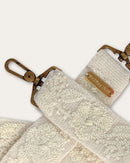 Close-up of the Coco bag strap by Ayni Ppacha: raised tone-on-tone embroidery on natural white sheep wool, brass-tone carabiner and plate engraved with Ayni Ppacha