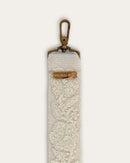 End of the Coco bag strap by Ayni Ppacha with brass-tone carabiner and engraved logo plate, natural white sheep wool with tone-on-tone hand embroidery
