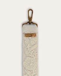 End of the Coco bag strap by Ayni Ppacha with brass-tone carabiner and engraved logo plate, natural white sheep wool with tone-on-tone hand embroidery