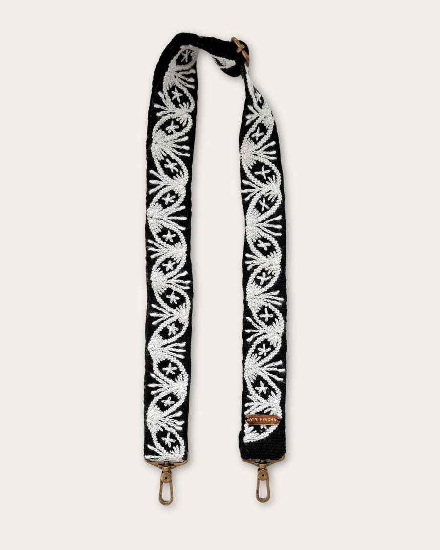 Taschengurt Lodoño von Ayni Ppacha in voller Länge: schwarze Schafwolle, handbestickt mit ovalen Medaillons, Sternblüten und Fächermotiven in Naturweiß, messingfarbene Karabiner