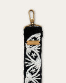 End of the Lodoño bag strap by Ayni Ppacha with brass-tone carabiner and engraved logo plate, black sheep wool with natural white hand embroidery
