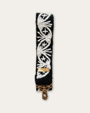 Section of the Lodoño bag strap by Ayni Ppacha: natural white medallion with star flower on black sheep wool, with logo plate and brass-tone carabiner below