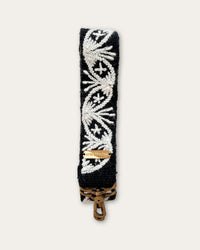 Section of the Lodoño bag strap by Ayni Ppacha: natural white medallion with star flower on black sheep wool, with logo plate and brass-tone carabiner below