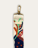 Riemenende des Taschengurts Piri Piri von Ayni Ppacha mit messingfarbenem Karabiner und gravierter Logoplakette, Ranken in Mint und Rost auf naturweißer Schafwolle