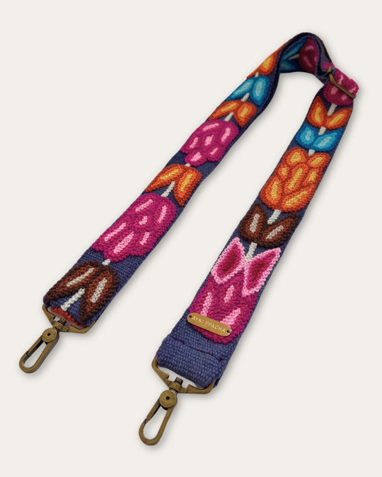Taschengurt Tulipán von Ayni Ppacha schräg ausgelegt: blaue Schafwolle mit handgestickten Tulpen in Pink, Orange und Türkis, verstellbarer Schieber und zwei messingfarbene Karabiner