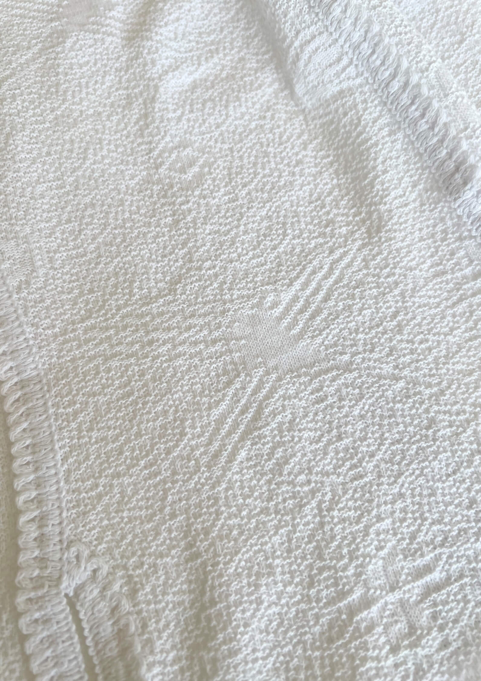 Makro-Ansicht des weißen Tops 'Baila' von Ayni Ppacha. Die architektonische Textur des Nazca-Webstoffs wird durch Häkeldetails (Crochet) ergänzt, die den puristischen Look veredeln.