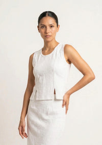 Das weiße Tanktop 'Baila' von Ayni Ppacha aus strukturiertem Nazca-Baumwollwebstoff. Die Aufnahme zeigt die puristische Silhouette mit den charakteristischen Seitenschlitzen und der filigranen Häkelkante.